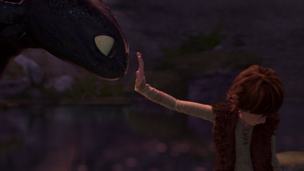 Still from the film. Hiccup reaches out to Toothless with his eyes closed as a sign of trust. 
